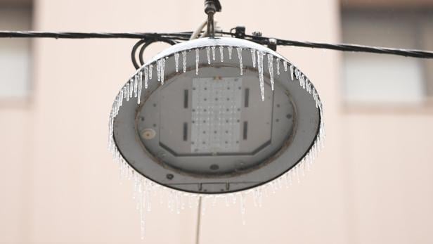 An einer Straßenlaterne hängen zahlreiche Eiszapfen herab.