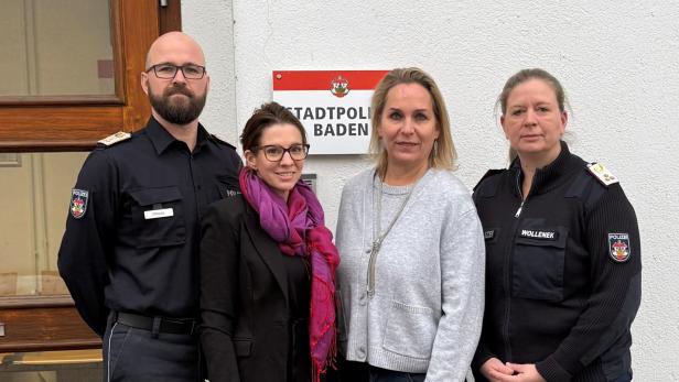 2 Polizisten und zwei Frauen vor einer Wand mit einem Schild "Stadtpolizei Baden"