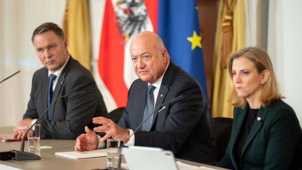 Drei Personen, es sind Stocker, Babler und Meinl-Reisinger, sitzen an einem Tisch vor österreichischen und EU-Flaggen.