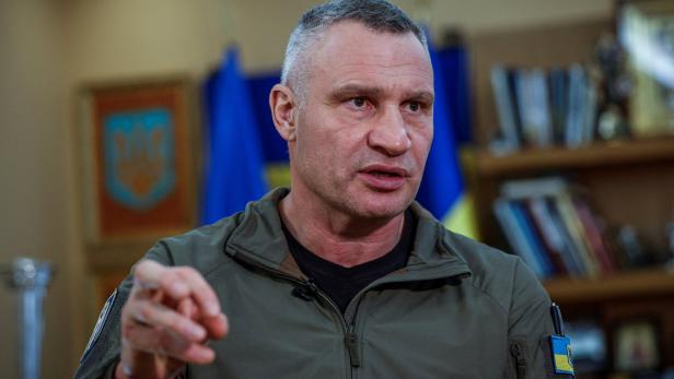 Vitali Klitschko gestikuliert vor ukrainischen Flaggen und einem Bücherregal.