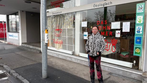 Eine Person steht vor einem Schaufenster mit der Aufschrift „Pannonische Tafel“ und bunten Bildern an der Scheibe.