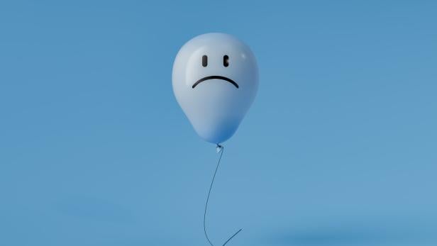 Ein blauer Ballon mit traurigem Gesichtsausdruck schwebt an einer Schnur vor blauem Hintergrund.