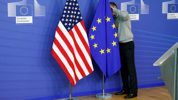 FILE PHOTO: A worker adjusts EU and U.S. flags at the EU Commission headquarters in Brussels