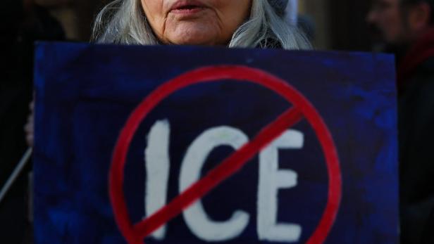 Eine Frau mit Tränen hält ein Schild mit der Aufschrift "ICE" in einem roten Verbotskreis.