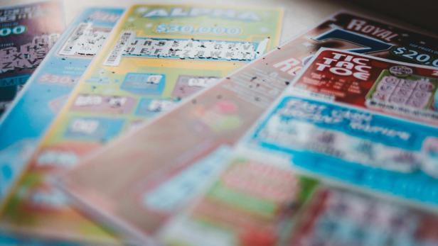 Mehrere bunte Rubbellose liegen nebeneinander auf einer Fensterbank.