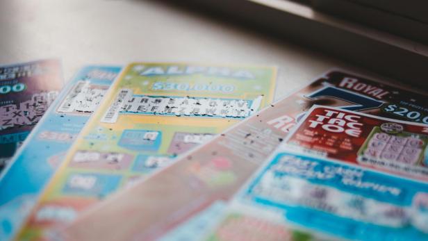 Mehrere bunte Rubbellose liegen nebeneinander auf einer Fensterbank.