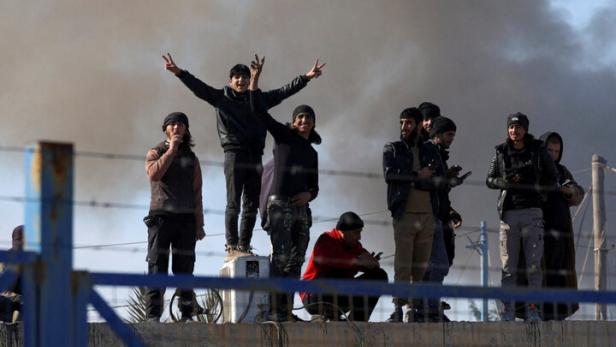 Männer hinter Stacheldraht jubeln