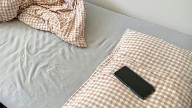 iPhone, welches auf einem Kissen liegt.