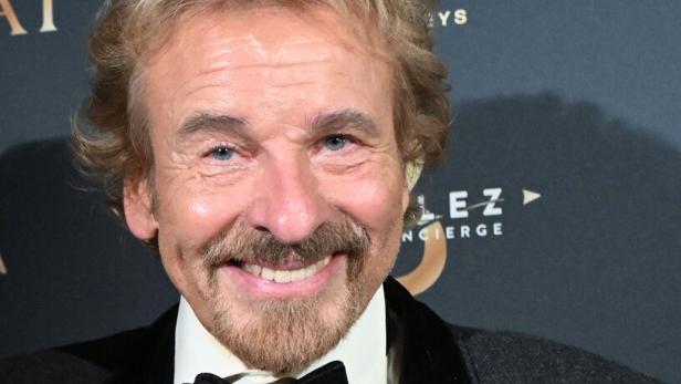 Thomas Gottschalk lächelt mit Fliege und einer goldenen Statue in der Hand.