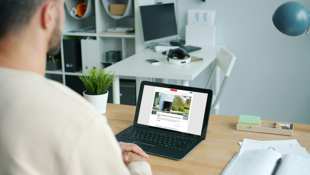 Ein Mann schaut auf einen Laptop mit offenen Artikel von KURIER zu Wärmepumpen.