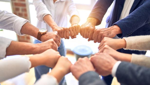 Group of business workers standing bumping fists at the office