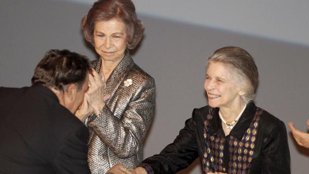 Prinzessin Irene lächelt und schüttelt einem Mann die Hand, während Altkönigin Sofía daneben steht und zuschaut.