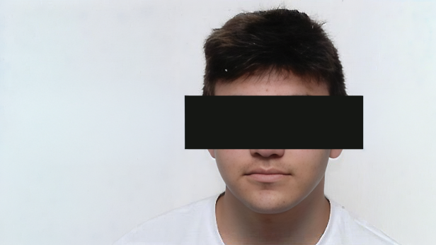 Hasan E. schaut direkt in die Kamera, seine Augen sind von einem schwarzen Balkan bedeckt