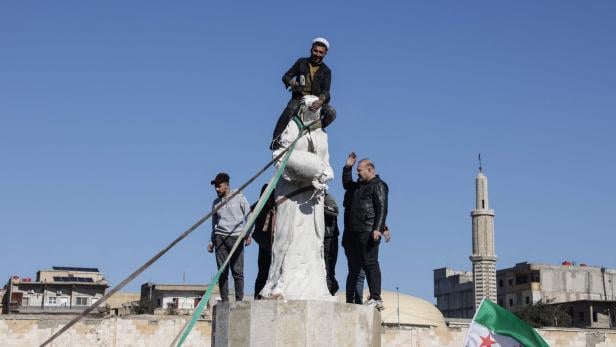 Araber  feiern die Vorstöße: Im Bild stürzen sie eine Statue der  kurdischen Frauenmiliz in ar-Raqqa.
