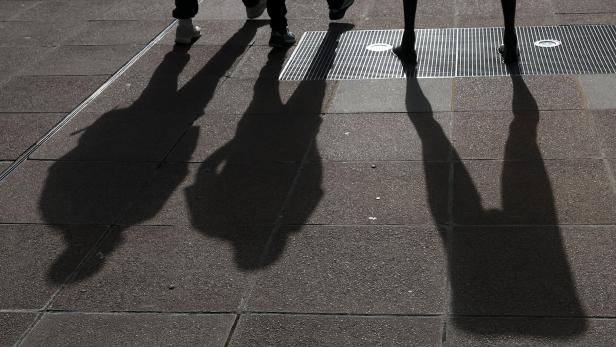 People are silhouetted as they walk past a sculpture in London