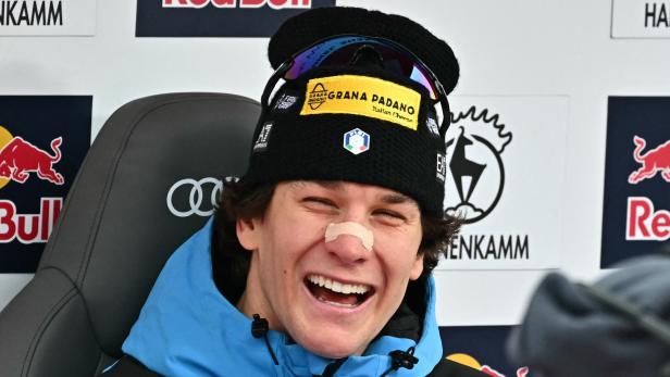 Giovanni Franzoni am Siegersessel in Kitzbühel mit Winterjacke und Mütze lacht breit, auf seiner Nase klebt ein Pflaster.