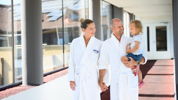 Eine Familie geht in Bademänteln durch ein Hotel 