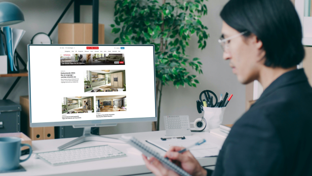 Eine Person arbeitet am Schreibtisch und betrachtet auf einem Monitor den Content Hub „Wohnwelt“ von XXXLutz auf der Kurier-Website.