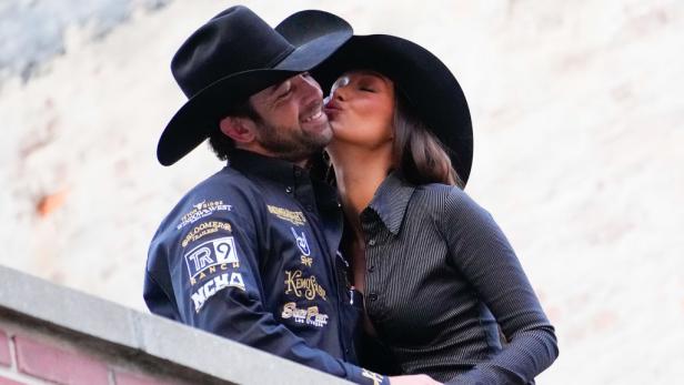 Bella Hadid und Adan Banuelos mit Cowboyhüten stehen eng beieinander, sie küsst ihn auf die Wange.