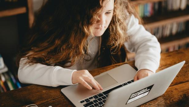 ein Mädchen sitzt vor einem Laptop 