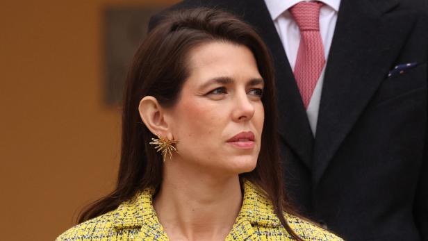 Charlotte Casiraghi mit langen braunen Haaren trägt ein gelbes Jackett und auffälligen goldenen Ohrschmuck.