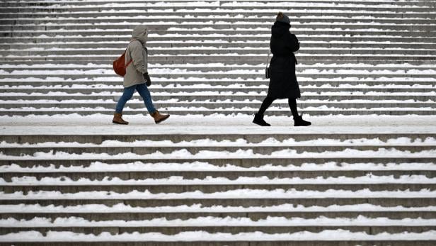 Zwei Personen gehen auf einer schneebedeckten Treppe entlang.