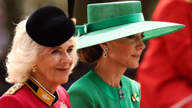 Camilla und Kate, beide mit Hut, schauen in die gleiche Richtung und lächeln.