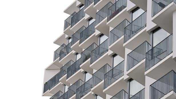 Mehrstöckiges Gebäude mit vielen modernen, versetzt angeordneten Balkonen und Glasfronten.