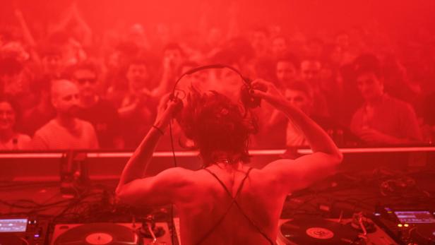 Tanzszene in einem Club mit DJane und grellem roten Licht