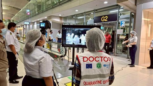 Airport health authorities wearing protective masks monitor passengers from international flights arriving at Suvarnabhumi International Airport