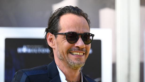 Marc Anthony lächelt mit Sonnenbrille und Anzug.
