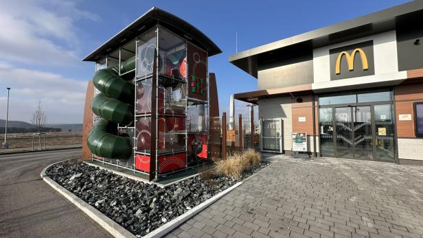 Ein moderner McDonald's mit einem großen, überdachten Kletter- und Rutschspielplatz im Außenbereich.