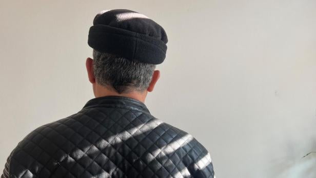 Syrischer Familienvater mit aufgestellter Mütze und schwarzer Lederjacke von hinten 