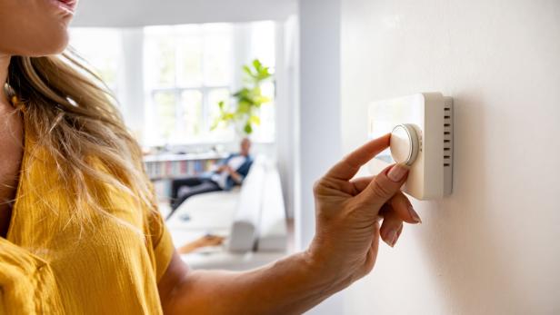 Eine Bewohnerin dreht am Thermostat  - weil es draußen kalt ist.