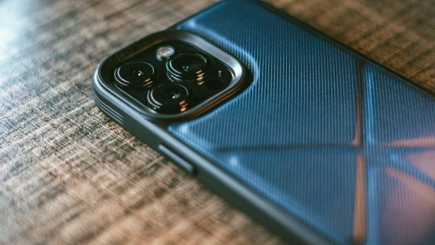 Smartphone mit blauer Schutzhülle liegt auf einer Holzoberfläche.