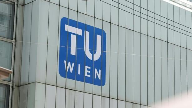 Das Logo der Technischen Universität Wien an einer modernen Gebäudefassade mit einer Straßenlaterne und Stromleitungen.