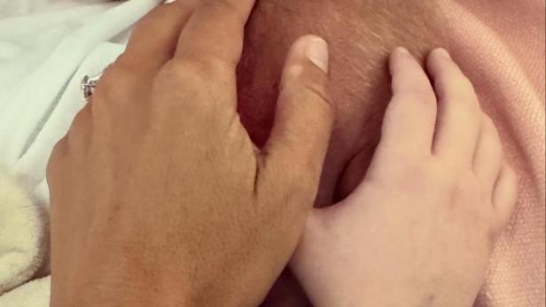 Drei Hände mit identischen Armbändern halten sich auf einer Decke.