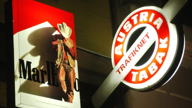 Leuchtende Werbeschilder für Marlboro-Zigaretten und Austria Tabak Trafik an einer Hauswand bei Nacht.