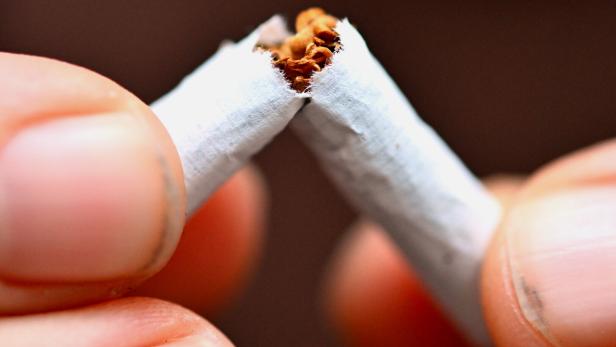 Zwei Finger zerbrechen eine Zigarette in der Mitte.