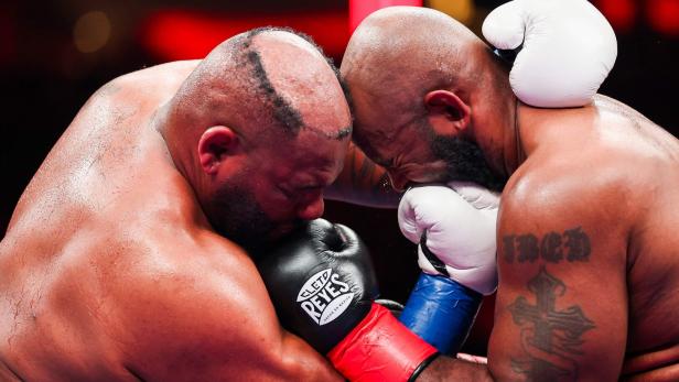 Zwei Boxer mit Boxhandschuhen stehen sich Stirn an Stirn gegenüber.
