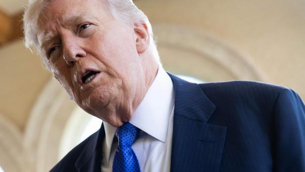 Donald Trump spricht mit blauem Anzug und Krawatte.