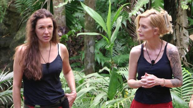 Simone Ballack und Mirja du Mont im Dschungelcamp stehen nebeneinander und tragen schwarze Tops.