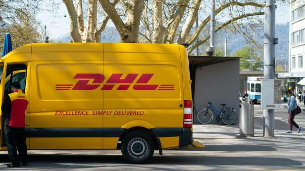 DHL-Lieferwagen mit Mitarbeiter an einer Haltestelle im Stadtgebiet.