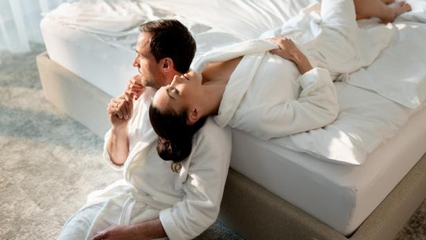 Eine Frau und ein Mann im Bademantel liegen gemütlich auf einem Bett und entspannen.