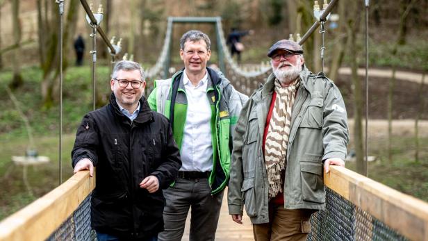 Drei Männer stehen auf einer Hängebrücke