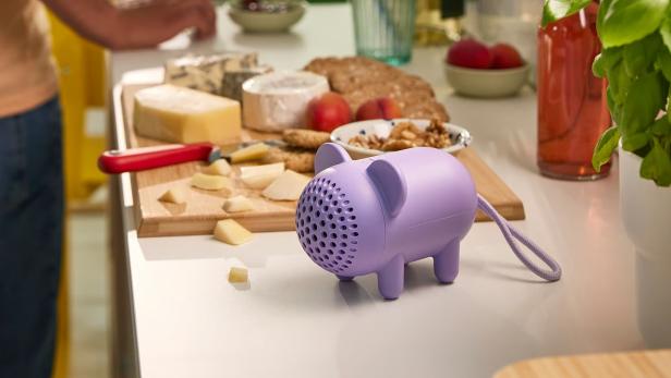 lila Maus-Lautsprecher auf einer Küchenarbeitsplatte, daneben ein Schneidebrett mit Käse