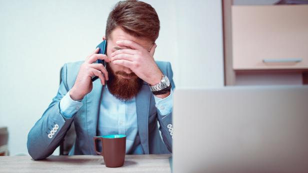 Worried and Exhausted Businessman Talking on Phone in his Office