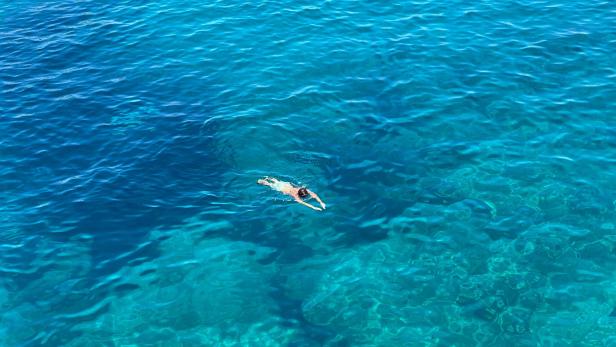 Ein Junge schwimmt allein im offenen, tiefblauen Meer vor der Küste von Westaustralien, um Hilfe für seine abgetriebene Familie zu holen.