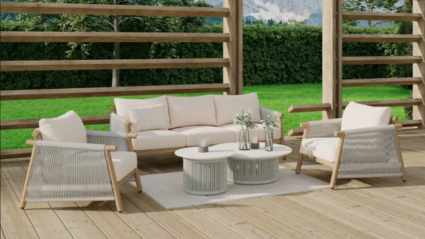 Helle Outdoor-Sitzgruppe mit Sofa, zwei Sesseln und zwei runden Tischen auf einer Holzterrasse, umgeben von viel Grün.
