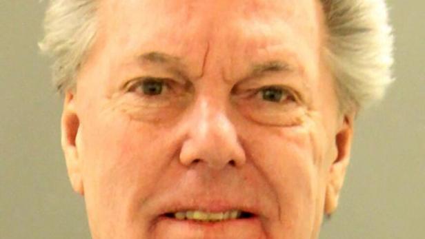 Ein älterer Mann mit grauen Haaren und grünem Pullover schaut direkt in die Kamera.